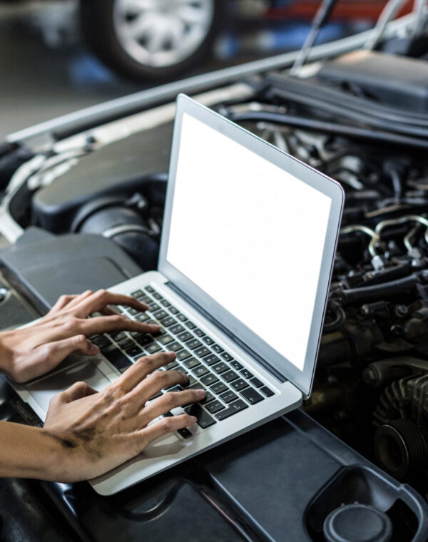 Hands of female mechanic using laptop in repair garage