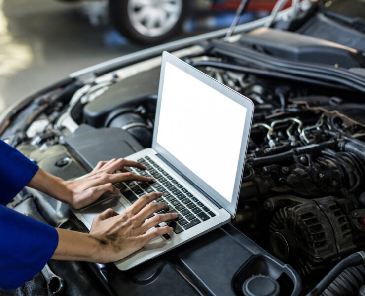 Hands of female mechanic using laptop in repair garage