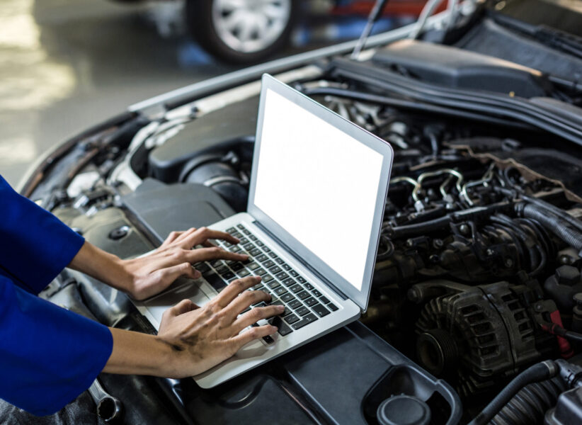 Hands of female mechanic using laptop in repair garage