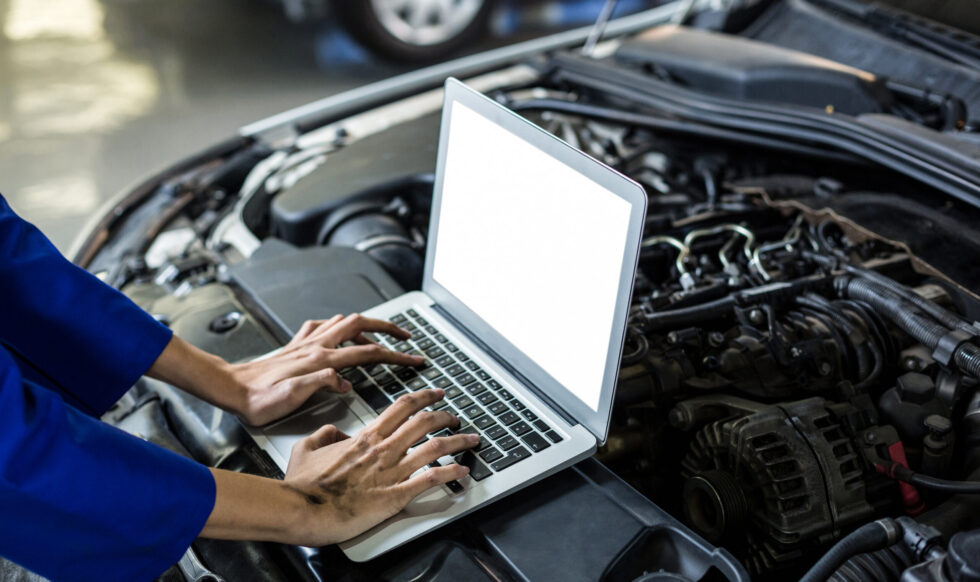Hands of female mechanic using laptop in repair garage